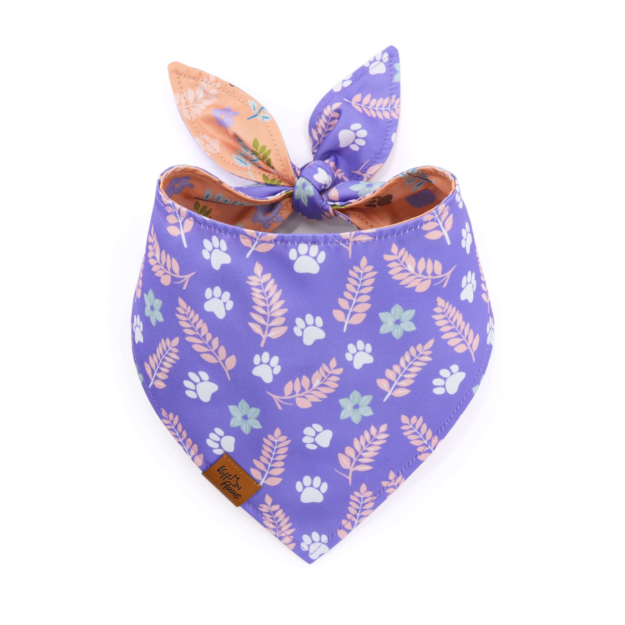 Purple dog bandana with floral and paw print patterns on a white background